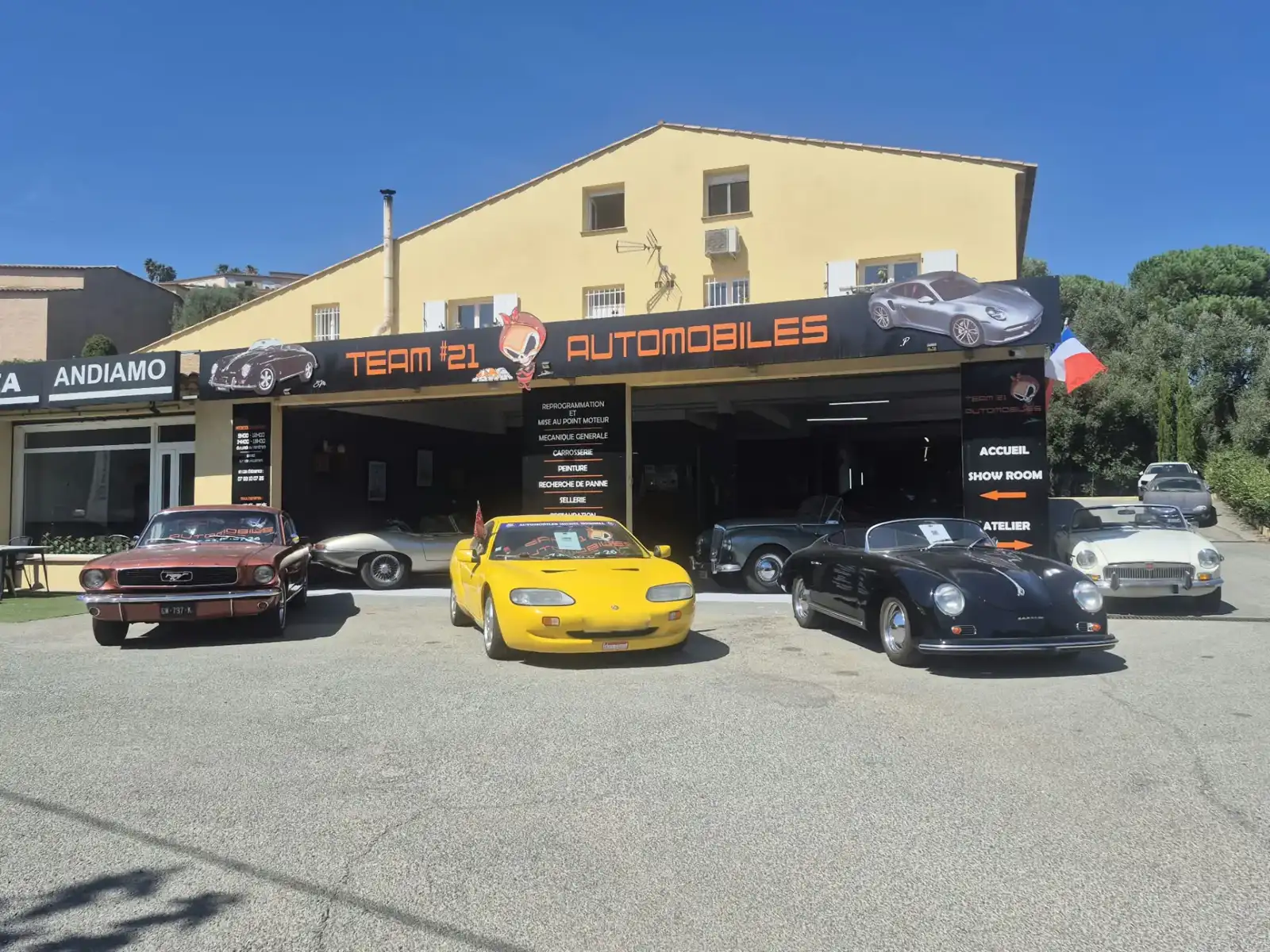 Façade du garage TEAM #21 AUTOMOBILES à Sainte-Maxime avec Mustang, Porsche 356 et voitures de collection